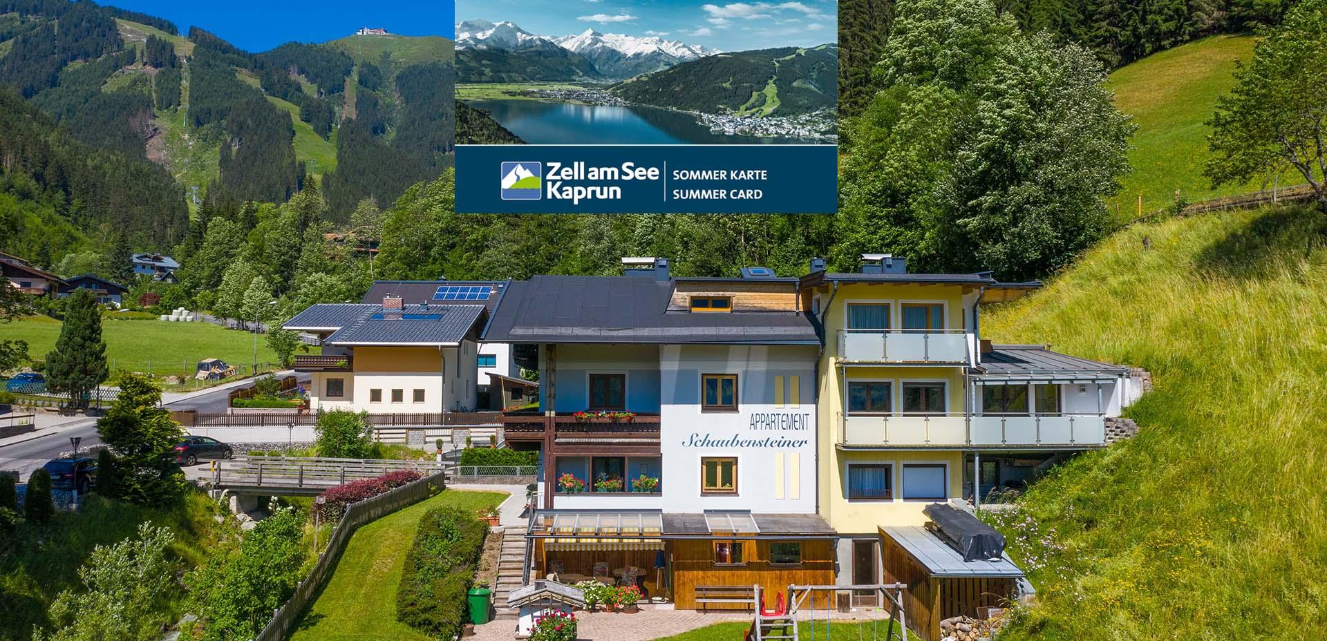 A modern building in the greenery with a view of the mountains. In the background, the Schmittenhöhe can be seen under a clear sky.