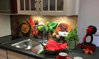 A modern kitchen with a stainless steel sink and decorative kitchen utensils. The wall is adorned with herbs and spices, and there are red mugs on the countertop.