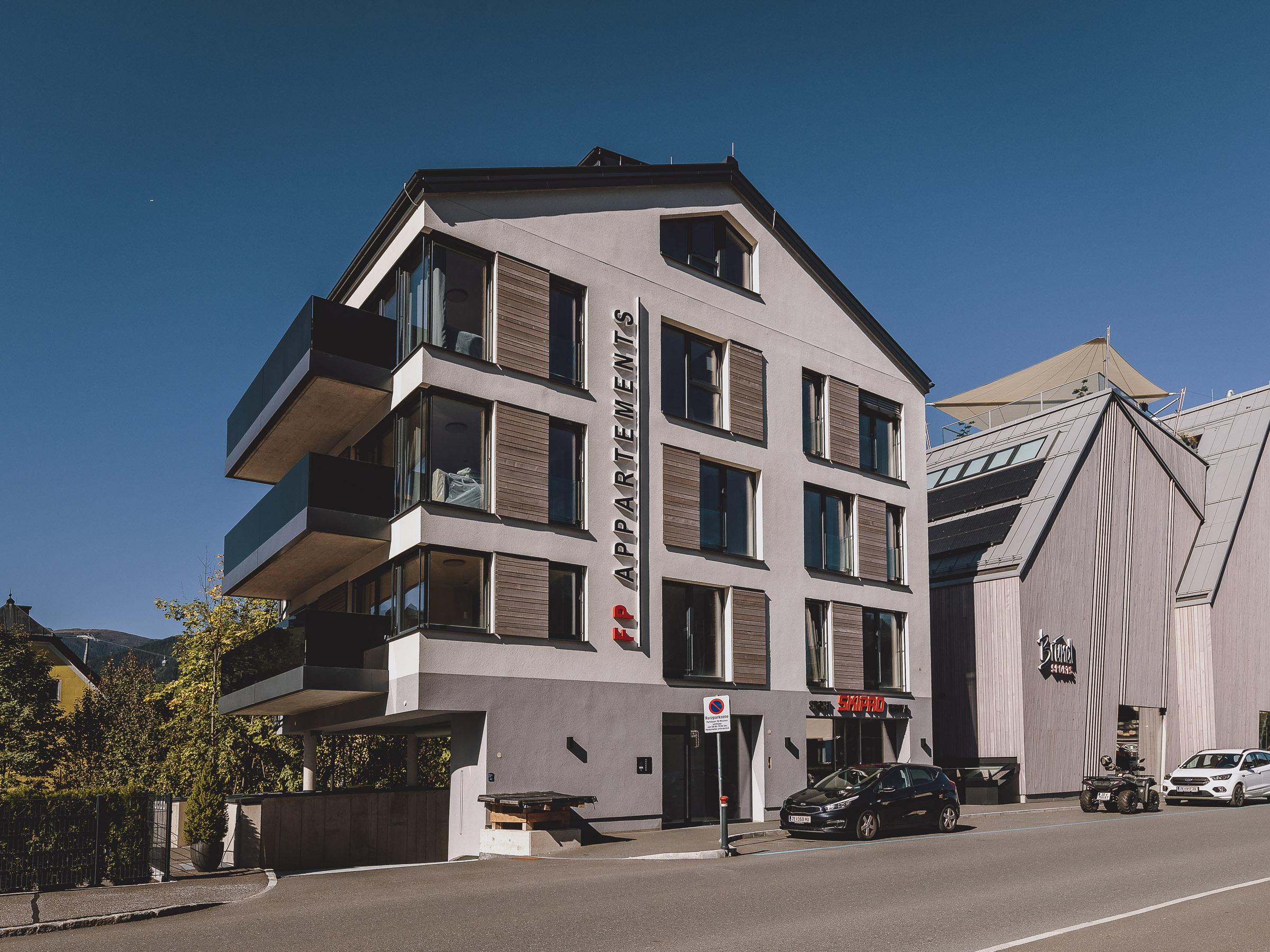 A modern building with apartments on a street. The facade is bright and features large windows.