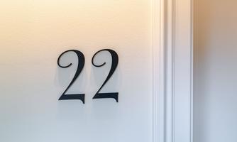 An elegant house number 22 on a white wall. The font is in a stylish, curved design.