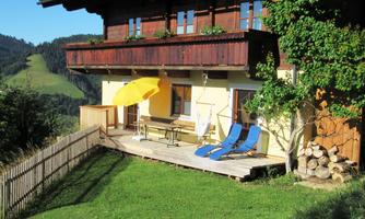 A cozy holiday home with a balcony and a terrace. The garden is green and equipped with lounge chairs and a sun umbrella to enjoy the view.