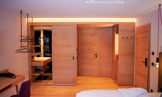 A modern room with wooden furniture and warm light. There is a desk, a wardrobe, and a pleasant atmosphere.