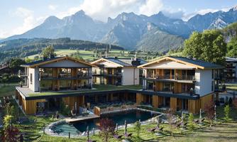 A modern facility with several buildings and a pool amidst a picturesque mountain landscape. The green garden invites you to relax.