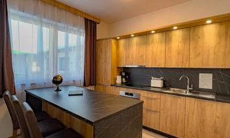 A modern kitchen with wooden cabinets and a large cooking island. The windows let in plenty of daylight and create a bright atmosphere.