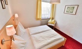 A cozy bedroom with a double bed and bright curtains. The walls are simple, and the room is well-lit.