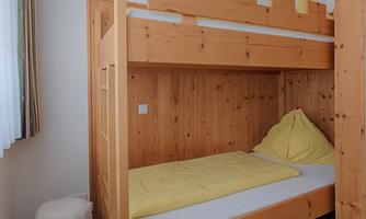 A cozy room with a wooden bunk bed. The room has a soft carpet and warm light.