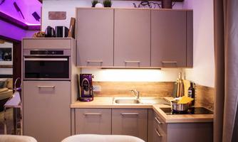 A modern kitchen with gray cabinets and a bright work area. The equipment includes an oven, a sink, and various kitchen appliances.