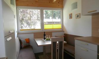 A bright, modern kitchen corner with a table and seating. The large windows let in plenty of light and offer a view of the outside.