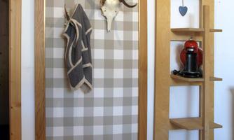 A decorative hallway with a checkered pattern and a deer antler. On the right, there is a shelf with a red coffee maker.