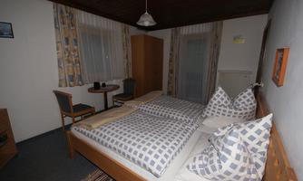 A cozy bedroom with two beds and checkered pillows. A small table and chairs complete the furnishings.