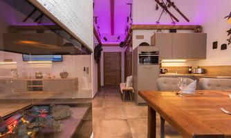A modern kitchen with wood decor and stylish furniture. Soft, colored light creates an inviting atmosphere.