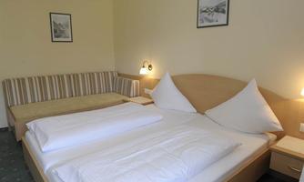 A cozy bedroom with a double bed and a seating area. The walls are in neutral colors and there are two framed pictures.