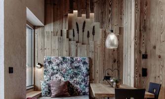 A modern room with wooden decor and a cozy sleeping nook. A table and chairs complement the inviting space.