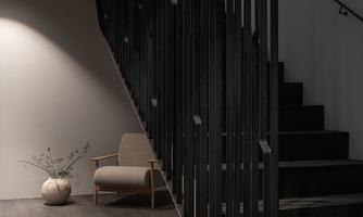 A modern staircase with an elegant railing. A cozy armchair and a decorative plant are located in the room.