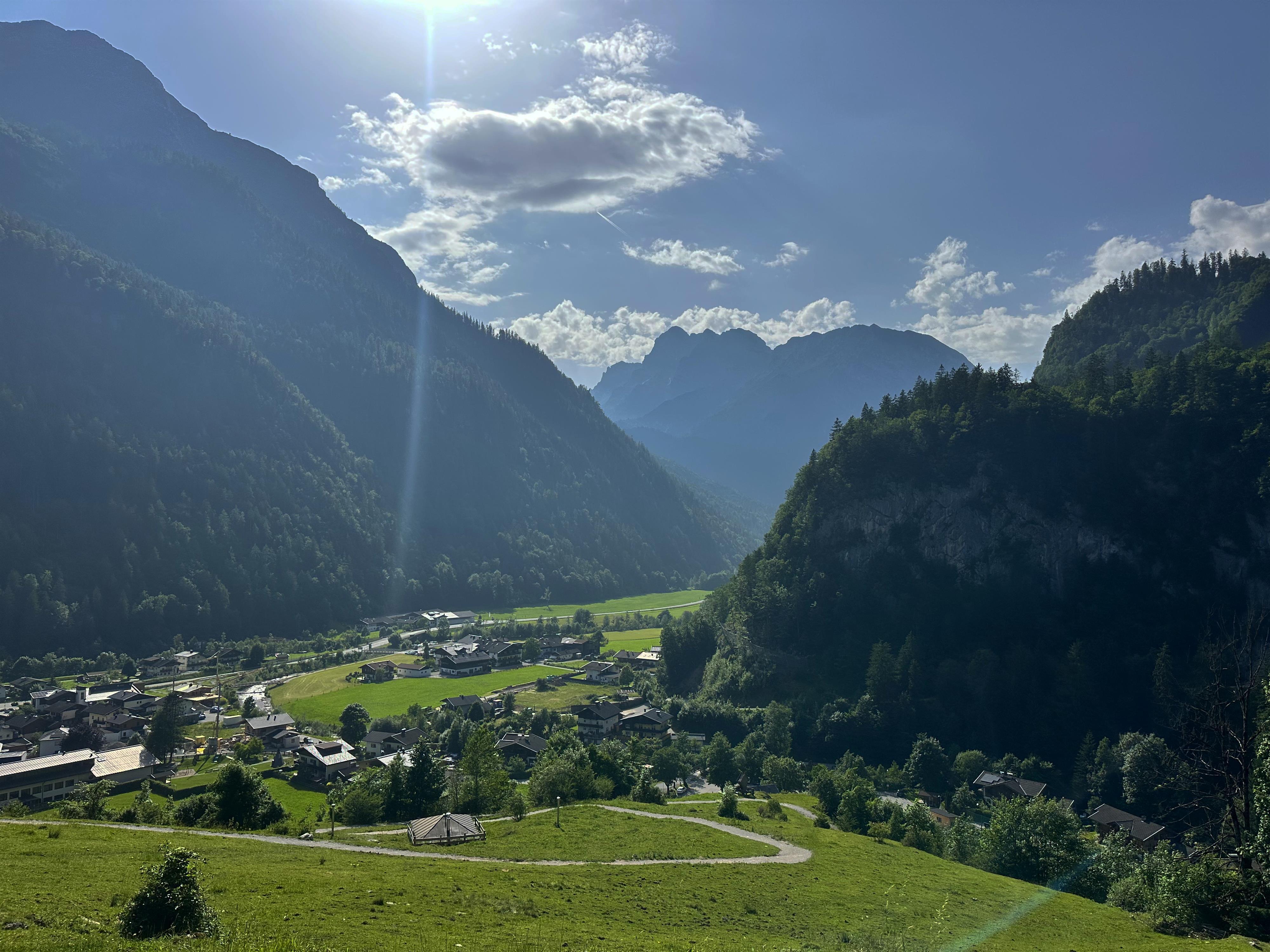 A picturesque mountain landscape with green meadows and shady valleys. In the background, majestic mountains rise under a clear sky.