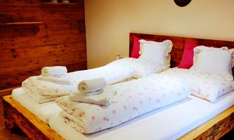 A cozy bedroom with a wooden bed and soft pillows. The walls are made of wood, and the decor exudes a warm atmosphere.