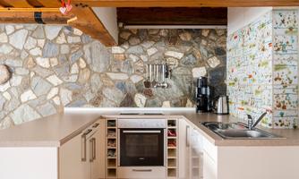 A modern kitchen with a stone wall and bright cabinets. The equipment includes a stove, sink, and kitchen appliances.
