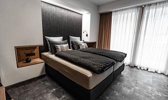 A modern bedroom with a double bed and elegant bedding. Large windows let in plenty of light and create an inviting atmosphere.