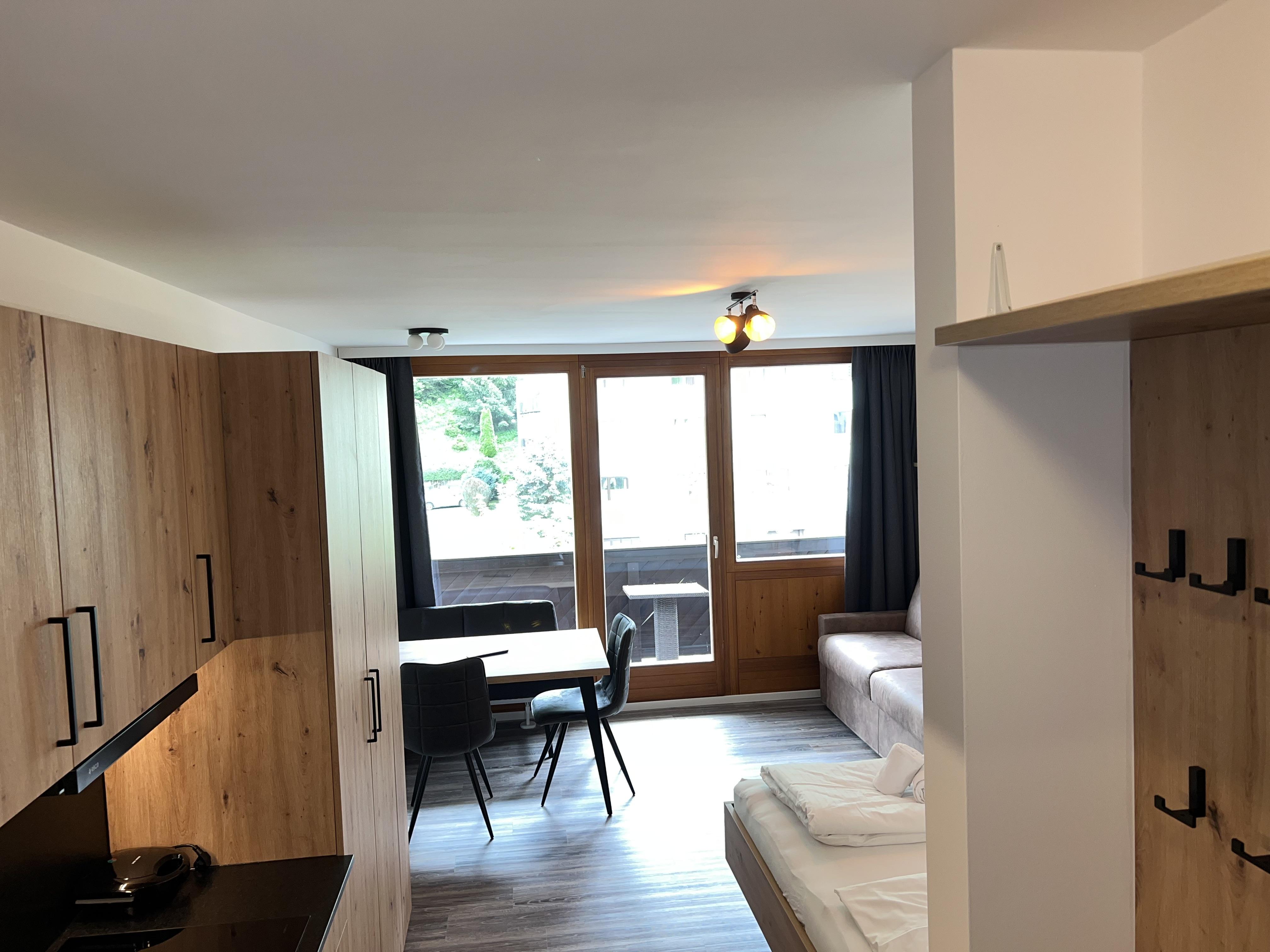 A modern apartment with wooden cladding. The room features a cozy seating area and large windows with a view of the outdoors.