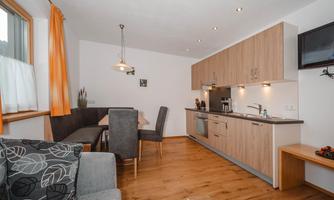 A modern kitchen with wooden cabinets and a dining area. The space is well-lit and has a cozy atmosphere.