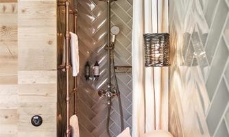 A modern shower with tiled walls and wooden elements. The bathroom is bright and tastefully designed.