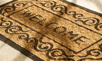 Welcome mat with a curved pattern and the inscription "WELCOME". The mat has a natural color and is made of coconut fiber.