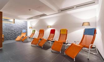 A relaxing space with colorful loungers and soft lighting. The walls are designed in neutral tones, creating a calm atmosphere.