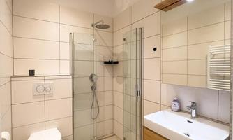 A modern bathroom with a shower and a wooden sink. The walls are brightly tiled and there is pleasant lighting.