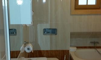 A modern bathroom with a bathtub, sink, and toilet. Bright tiles and a window provide plenty of light.