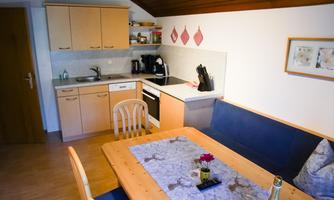A cozy kitchen with a dining table and seating area. The bright wooden cabinets and modern amenities create an inviting atmosphere.