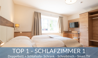 A modern bedroom with a double bed and a sofa bed. The room is bright and friendly, with a desk and a Smart TV.