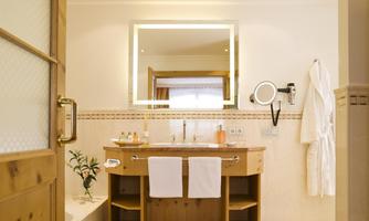 An elegant bathroom with wooden details and a large mirror. It is brightly lit and invites relaxation.