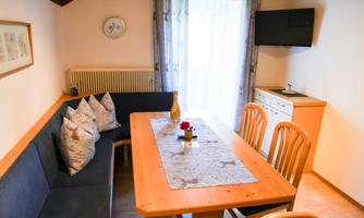 A cozy dining area with a wooden table and benches. The room has windows with plenty of light and modern decor.