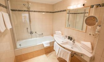 A modern bathroom with a bathtub and a shower. 
There are two sinks and fresh towels.