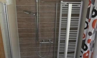 A modern bathroom with a shower and a towel warmer. The walls are decorated with brown tiles, and the space feels bright and inviting.
