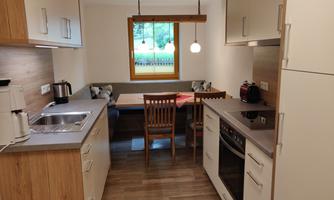 A modern kitchen with wood and white elements. The dining area with a window offers a cozy view of the outdoors.