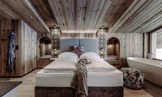 A modern bedroom with wooden walls and a large double bed. The cozy atmosphere is enhanced by the warm colors and stylish details.