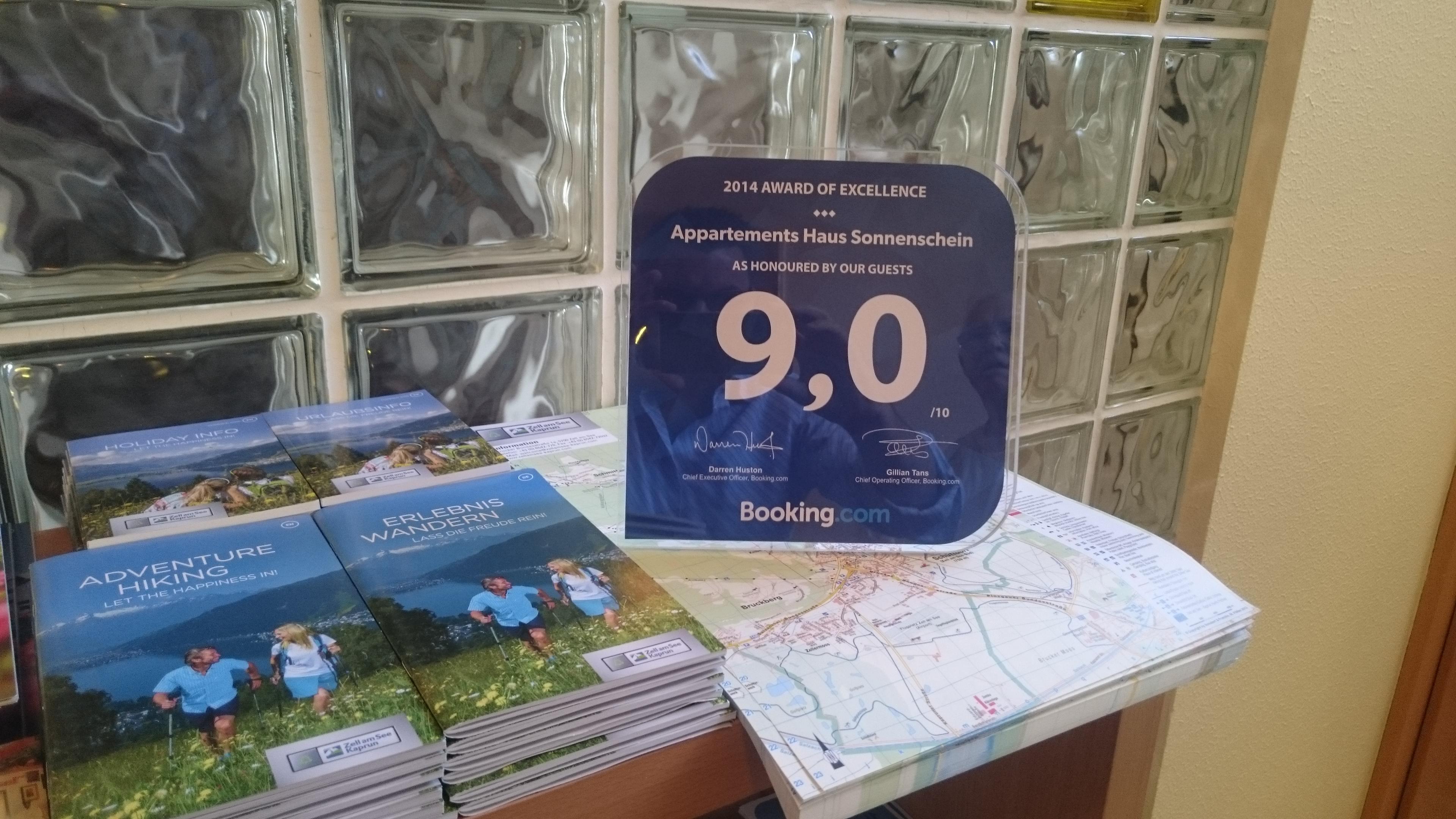 An award from Booking with a rating of 9.0 on a table. Next to it are brochures and a map.
