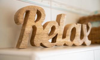 A wooden sign with the word "Relax". It stands decoratively on a shelf and conveys a relaxed atmosphere.