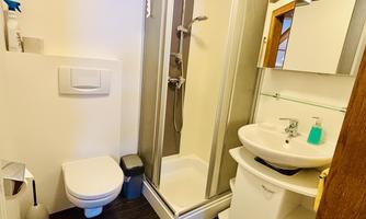 A modern bathroom with a shower, sink, and toilet. The furnishings are functional and well-organized.