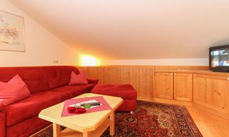 A cozy living room with a red sofa and wood paneling. A table with a small decoration is in the foreground.