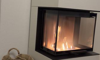 A modern fireplace with a blazing fire. Next to it stands a woven basket.