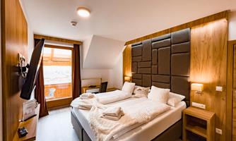 A modern hotel room with two beds, wooden panels, and warm lighting. The view of the balcony creates an inviting atmosphere.
