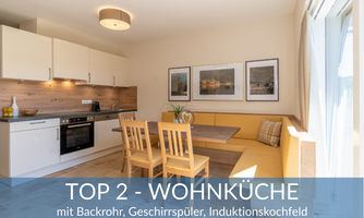 A modern kitchen-living room with a bright design. There is a dining table with chairs and a fully equipped kitchenette.