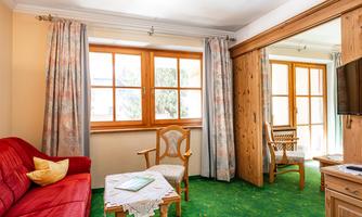 A cozy room with a red sofa and light curtains. Large windows let in plenty of light and create an inviting atmosphere.