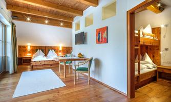 A bright and modern room with a wooden ceiling and cozy beds. It features a small living area with a table and chairs.