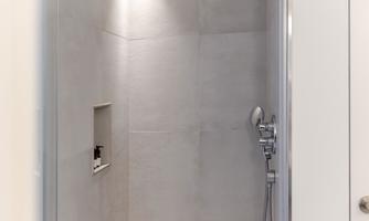 A modern shower with smooth, bright walls and a handheld showerhead. The space feels clean and inviting.