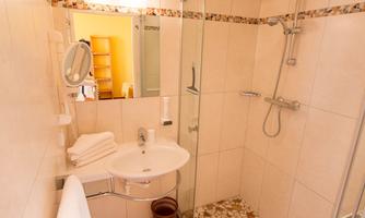 A modern bathroom with a shower and a sink. It features bright tiles and a large mirror.
