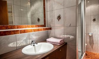 A modern bathroom with a washbasin and a shower cabin. The walls are decorated with elegant tiles.