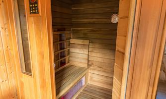 A modern wooden sauna with benches and a digital control panel. The room exudes a relaxing atmosphere.